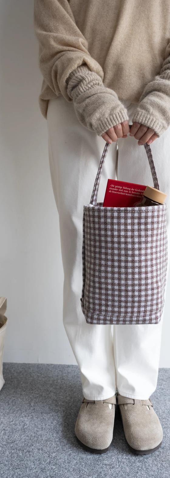 A woman holding a checked cotton canvas Tembea tote bag