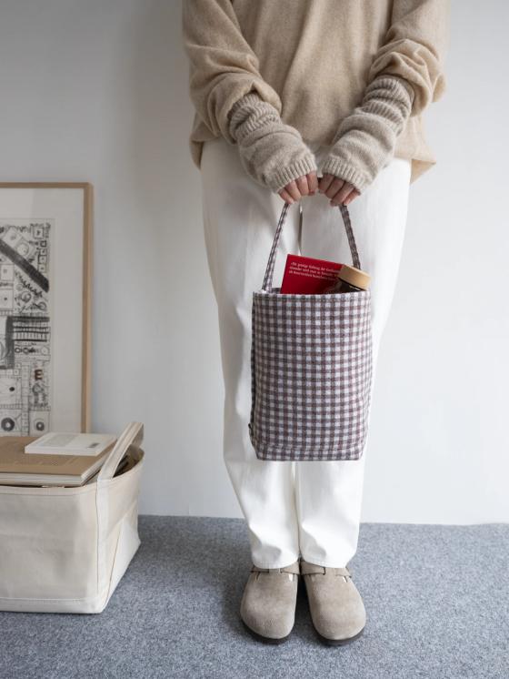 A woman holding a checked cotton canvas Tembea tote bag