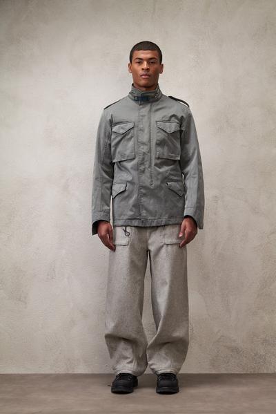 A man wearing a grey Ten C field jacket with grey wide-leg cargo trousers