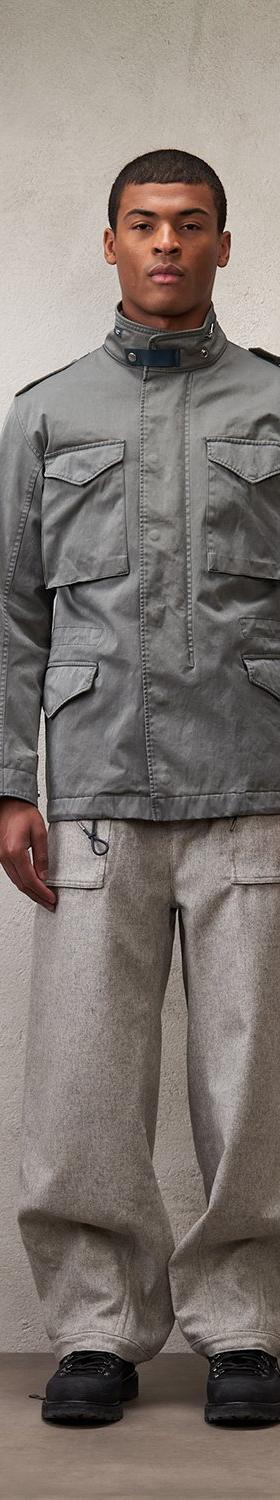 A man wearing a grey Ten C field jacket with grey wide-leg cargo trousers