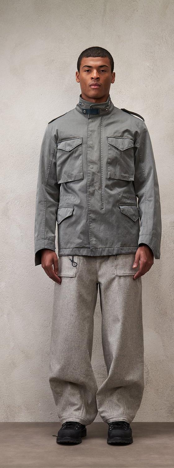 A man wearing a grey Ten C field jacket with grey wide-leg cargo trousers