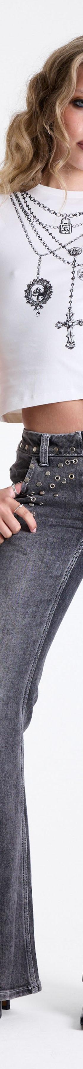 A woman wearing studded grey flared The Ragged Priest jeans with a white baby tee and layered cross chains