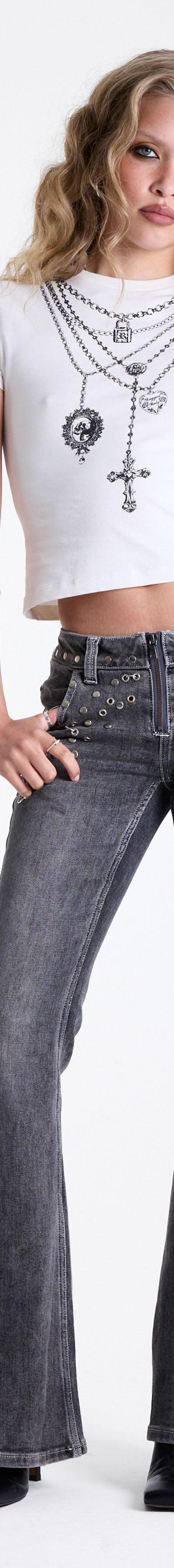 A woman wearing studded grey flared The Ragged Priest jeans with a white baby tee and layered cross chains