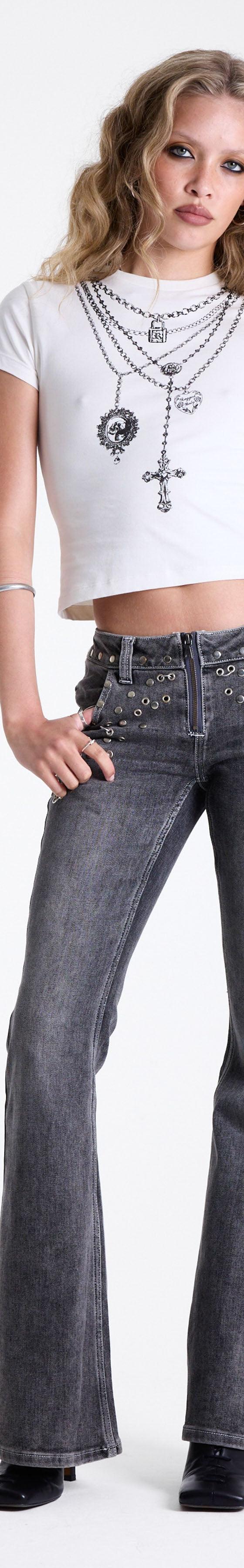 A woman wearing studded grey flared The Ragged Priest jeans with a white baby tee and layered cross chains