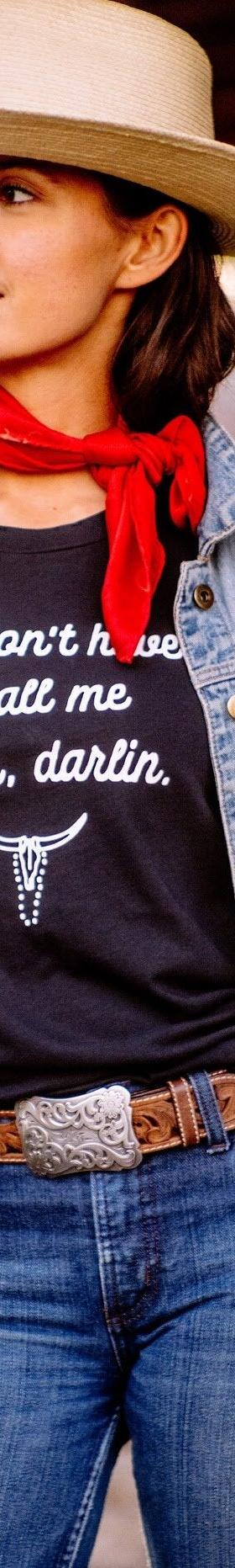 A woman wearing a straw wide-brim hat, denim jacket and red neckerchief with a black The Salt Ranch tee