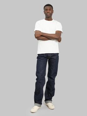 A man wearing slubby indigo The Strike Gold selvedge jeans with a natural white loopwheeled tee