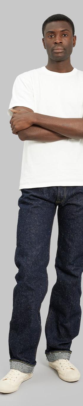 A man wearing slubby indigo The Strike Gold selvedge jeans with a natural white loopwheeled tee