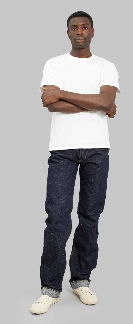 A man wearing slubby indigo The Strike Gold selvedge jeans with a natural white loopwheeled tee