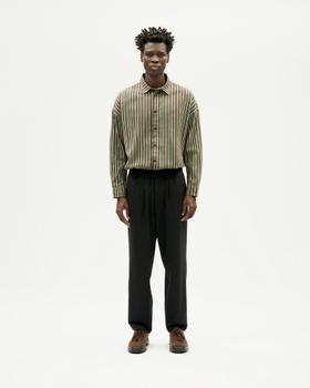 A man wearing a green striped Thinking MU shirt and black pleated trousers