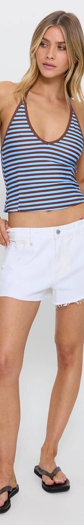 A woman wearing a navy striped Thrills halter tank with white denim cut-off shorts