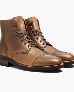 A pair of natural tan Thursday Boot Company Captain cap-toe leather boots on a plain white background