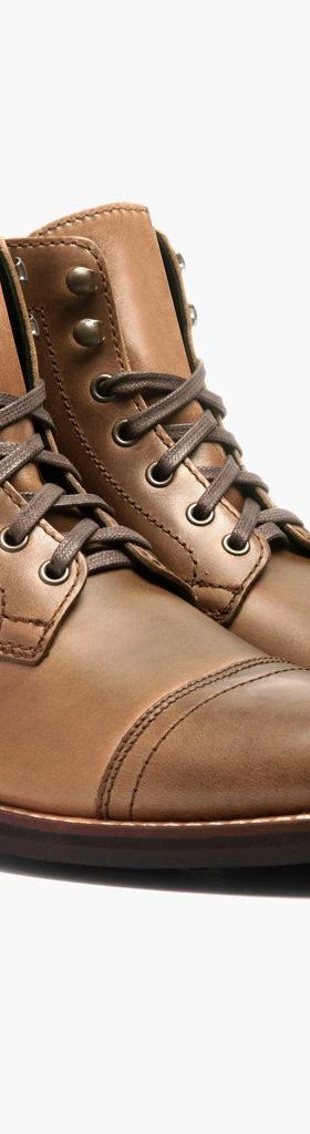 A pair of natural tan Thursday Boot Company Captain cap-toe leather boots on a plain white background