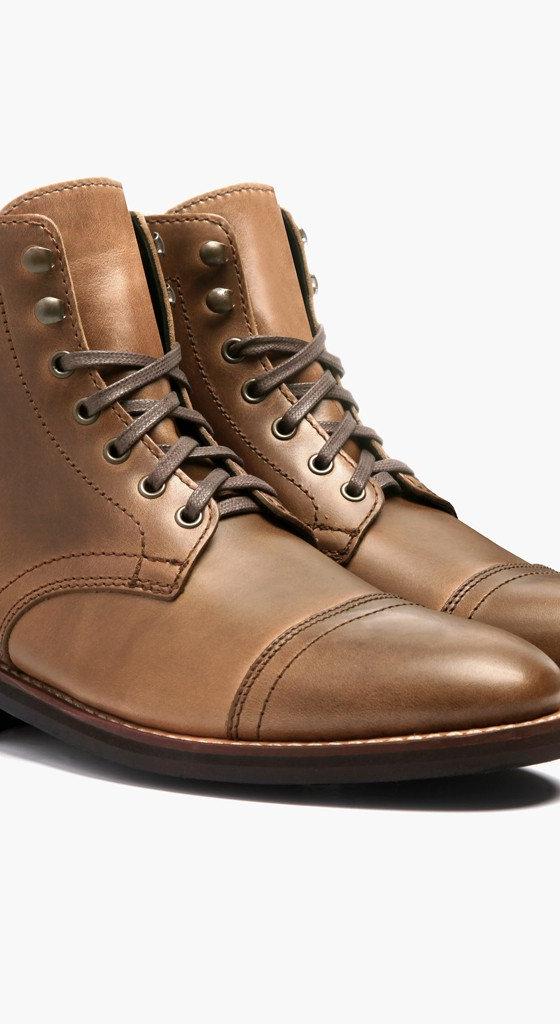 A pair of natural tan Thursday Boot Company Captain cap-toe leather boots on a plain white background