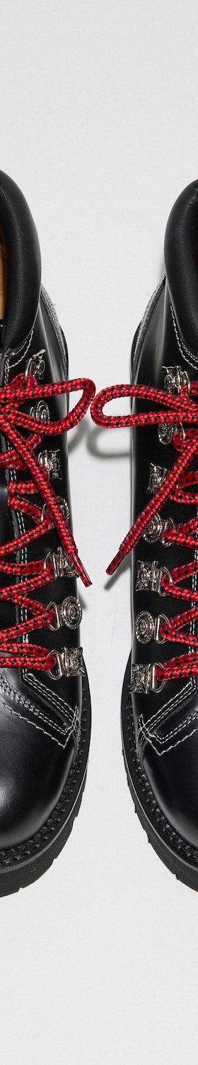 A pair of black TOGA Archives leather hiking boots with metal hardware and red laces