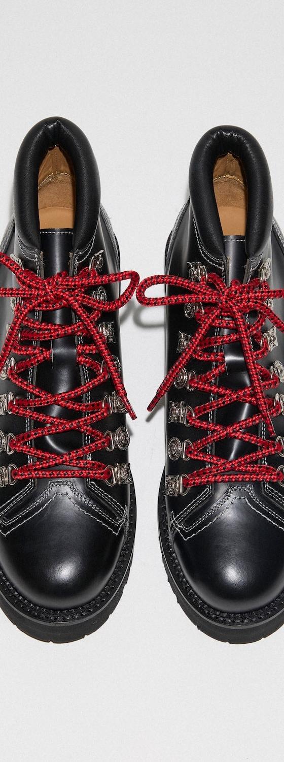 A pair of black TOGA Archives leather hiking boots with metal hardware and red laces