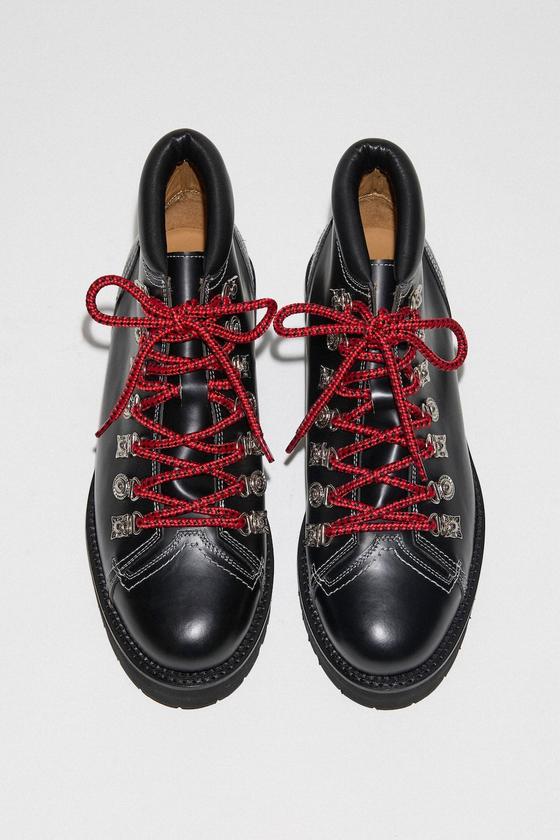 A pair of black leather Toga Virilis hiker boots with silver hardware and red laces