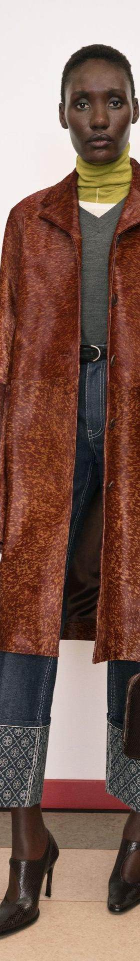 A woman wearing a brown printed leather coat with a leather belt and carrying a dark brown leather doctor's bag