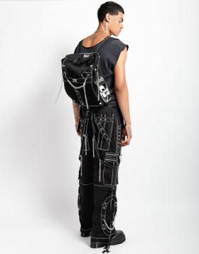 Tripp NYC model in black chained cargo pants with a studded skull backpack