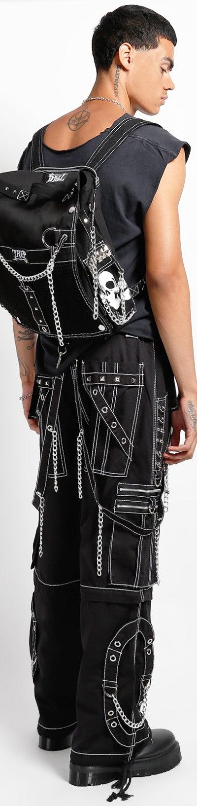 Tripp NYC model in black chained cargo pants with a studded skull backpack