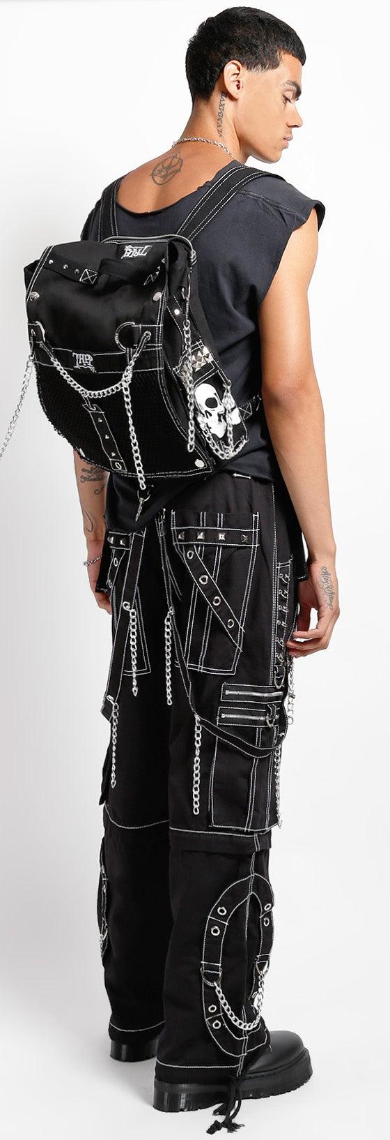 Tripp NYC model in black chained cargo pants with a studded skull backpack