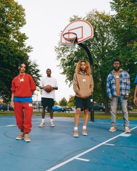 A group wearing Two18 sweatshirts, hoodies and track pants with tan sneakers on a Detroit basketball court