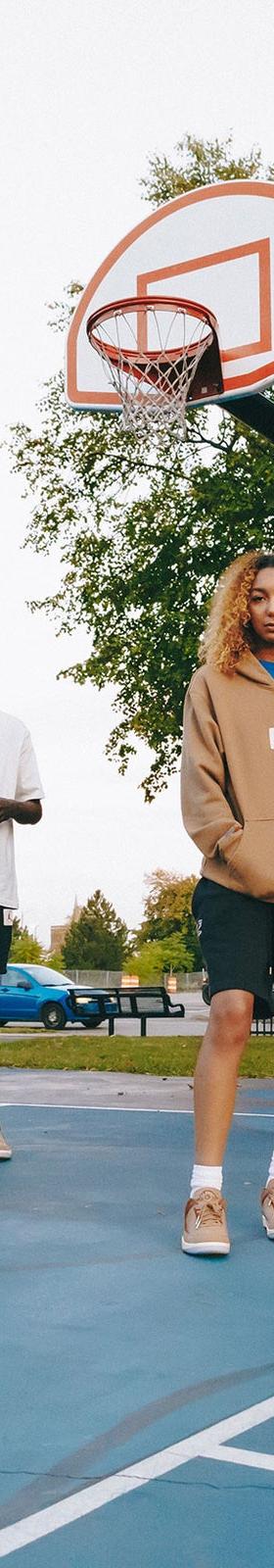 A group wearing Two18 sweatshirts, hoodies and track pants with tan sneakers on a Detroit basketball court