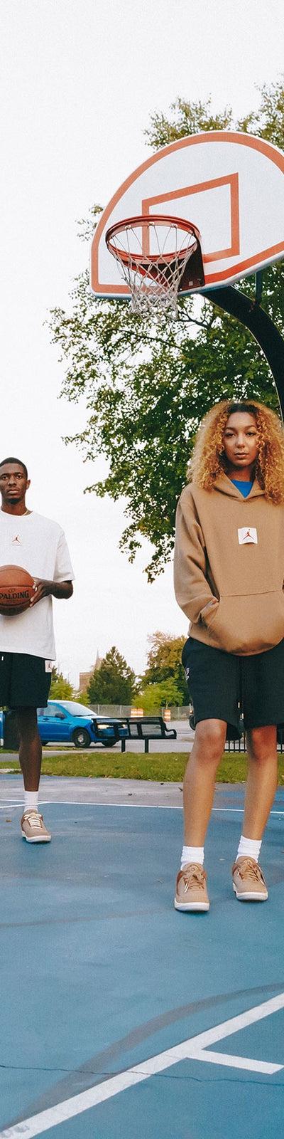 A group wearing Two18 sweatshirts, hoodies and track pants with tan sneakers on a Detroit basketball court