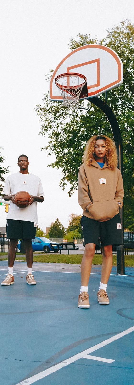 A group wearing Two18 sweatshirts, hoodies and track pants with tan sneakers on a Detroit basketball court