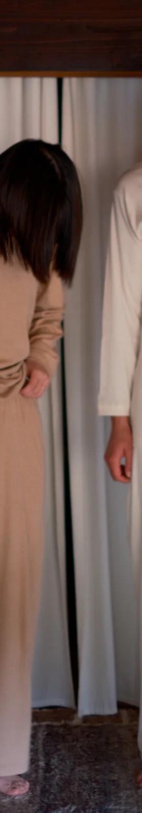 Two models wearing undyed cream and natural tan long-sleeve tops and wide-leg pants