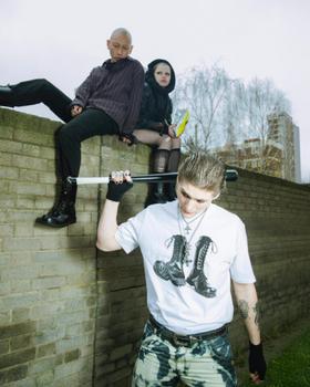 Three people in punk streetwear and black lace-up Underground England boots on a brick wall