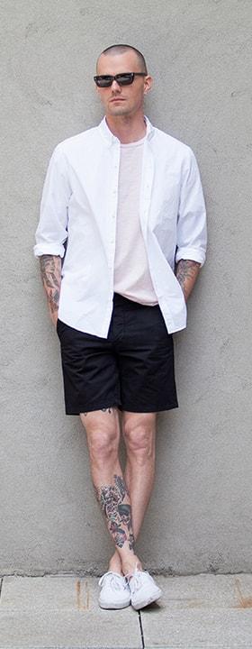 A man wearing a white Unis shirt with a pale tee and black shorts