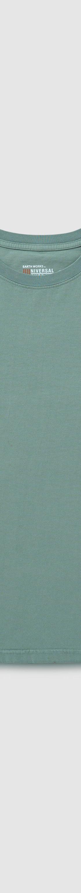 A sage green UNIVERSAL OVERALL long-sleeve cotton tee laid on a plain grey background