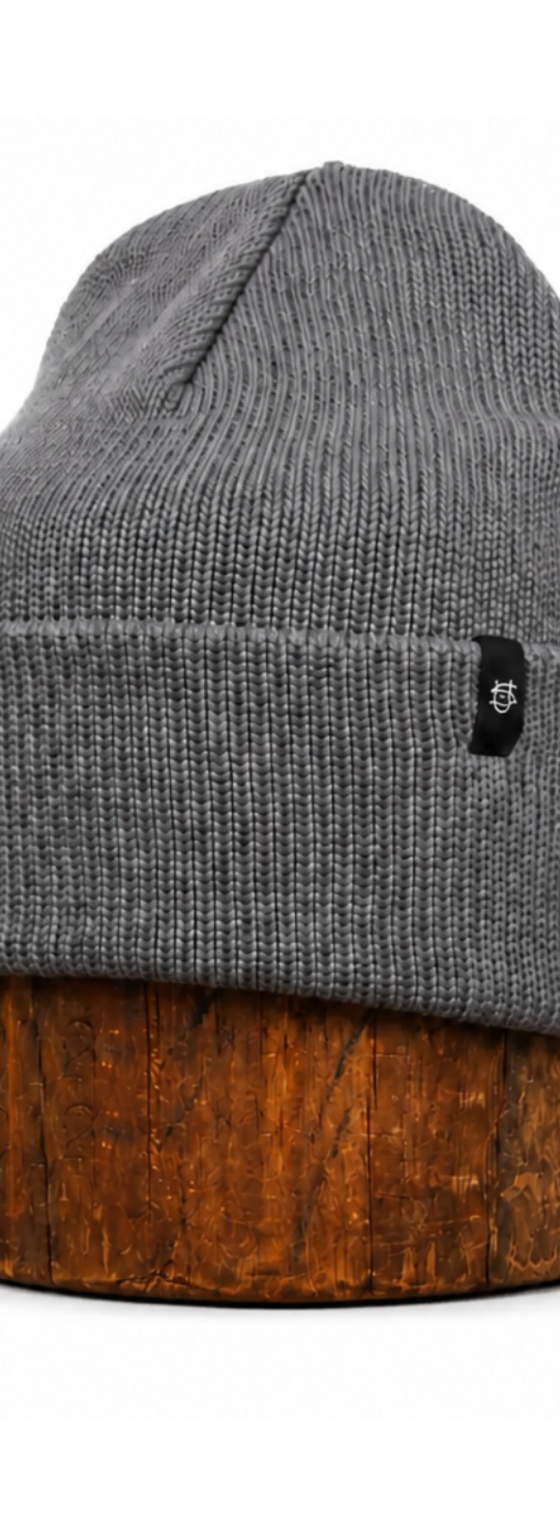 A grey ragg wool knit cap displayed on a wooden block
