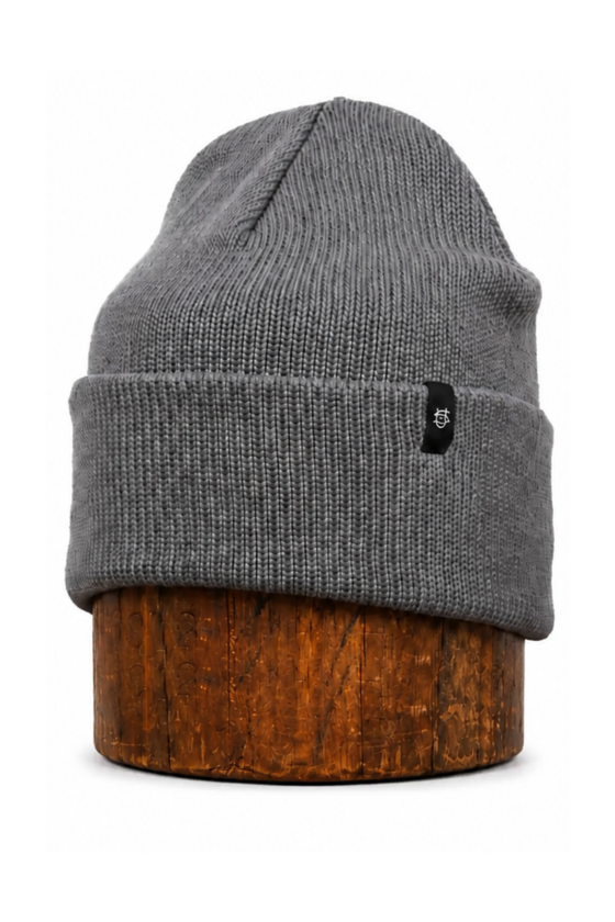 A grey ragg wool knit cap displayed on a wooden block