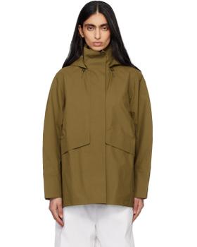 A woman wearing a khaki Veilance hooded technical jacket with white trousers