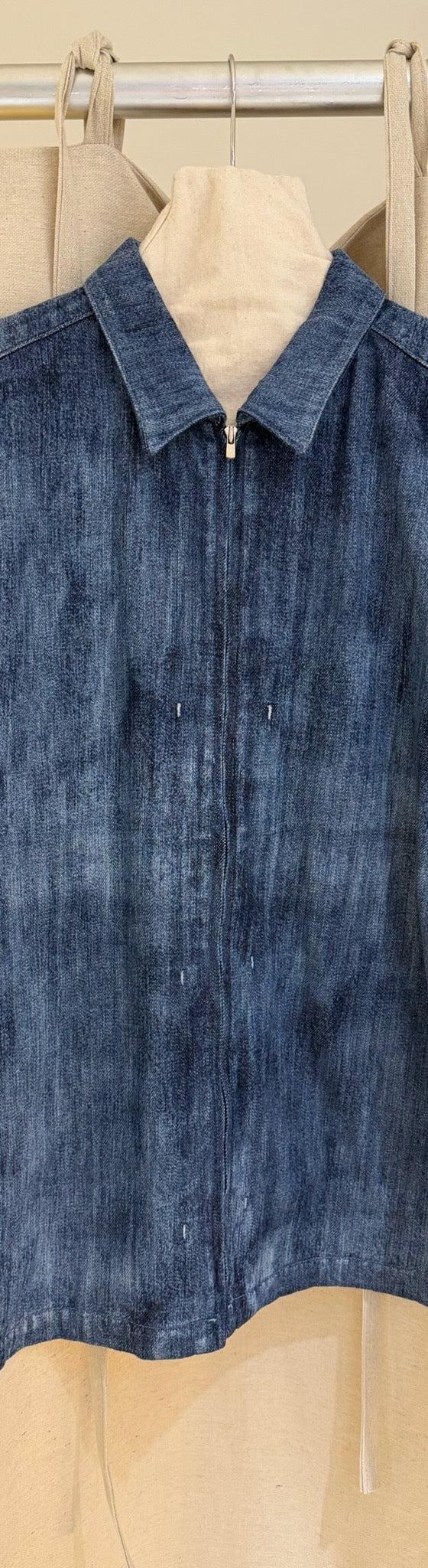An indigo denim zip jacket hung against a linen backdrop