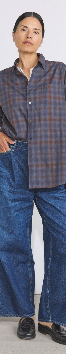 A woman wearing a checked Véritécoeur shirt with wide-leg denim jeans