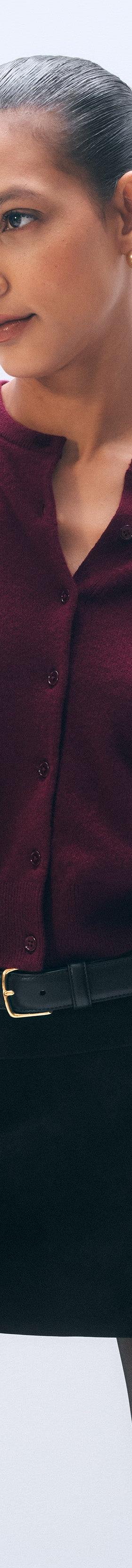 A woman wearing a burgundy White & Warren cashmere cardigan with a black suede mini skirt