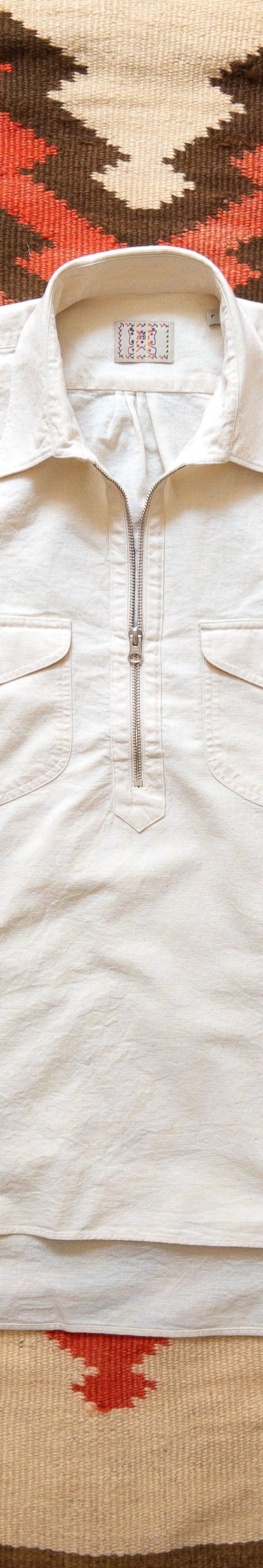 A cream Wythe half-zip popover workshirt laid flat on a woven Southwestern blanket