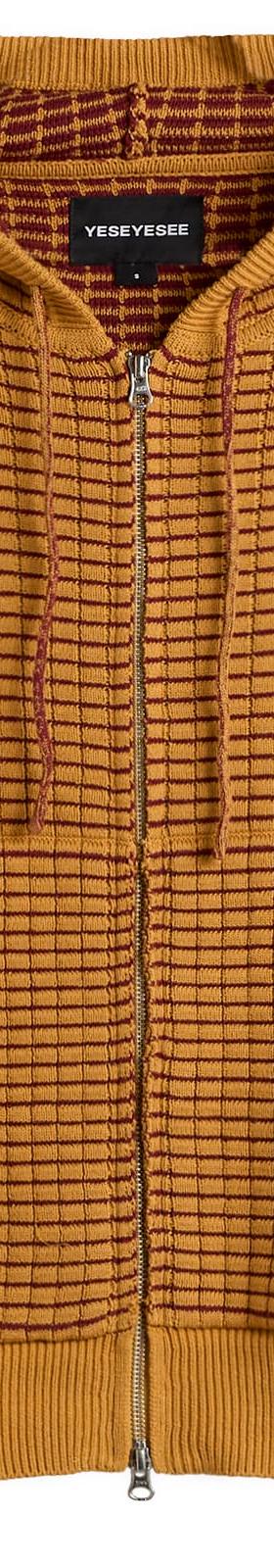 A mustard yellow waffle-knit zip-up hoodie with a burgundy embroidered logo