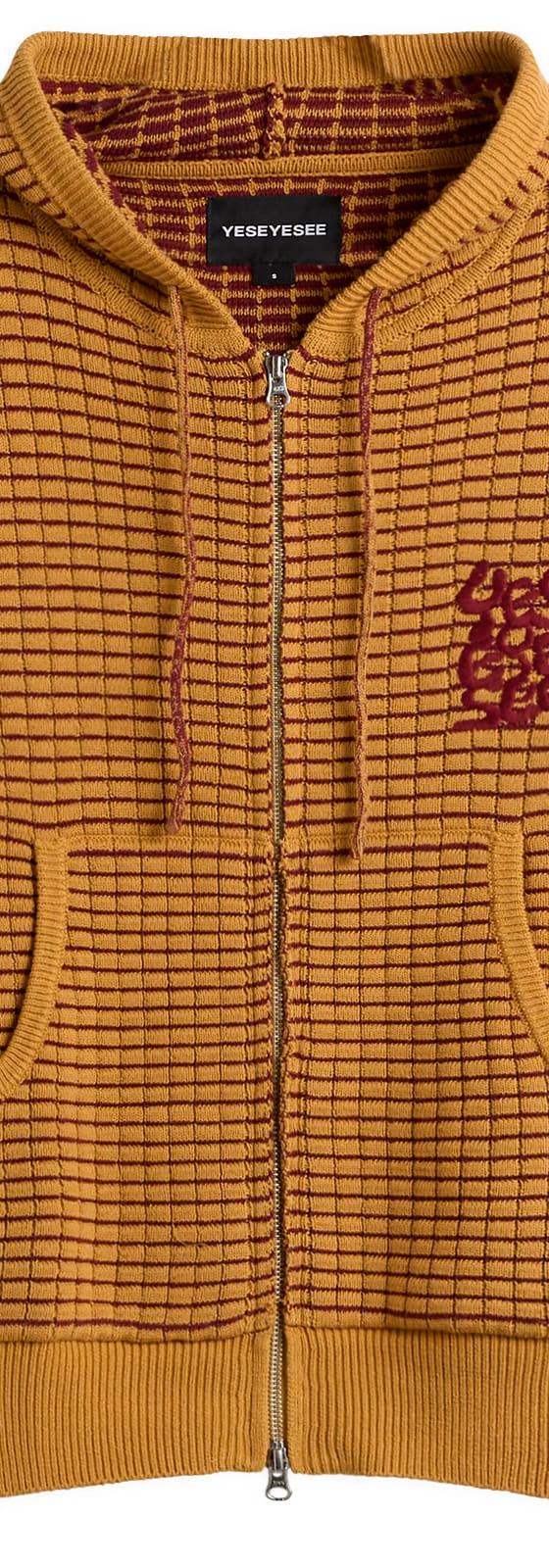 A mustard yellow waffle-knit zip-up hoodie with a burgundy embroidered logo