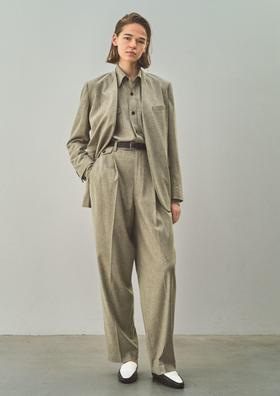 A woman wearing an oatmeal YLÈVE wool jacket and wide-leg trousers