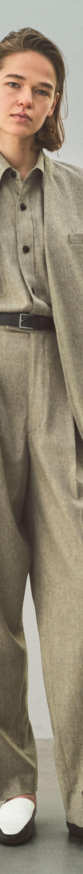 A woman wearing an oatmeal YLÈVE wool jacket and wide-leg trousers