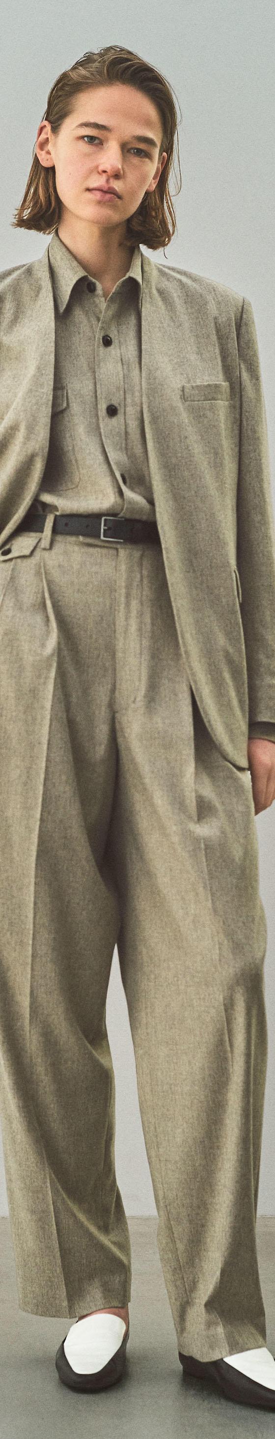 A woman wearing an oatmeal YLÈVE wool jacket and wide-leg trousers
