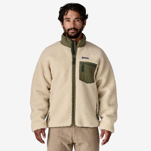 A man wearing a natural cream pile Classic Retro-X fleece jacket with an olive green collar, zip chest pocket and center zip trim, over tan corduroy trousers, against a plain white studio background.