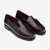 A pair of men's polished brown-burgundy leather penny loafers with hand-stitched moc toes, penny straps and dark stacked soles, shown at a three-quarter angle on a pale grey background.