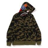A Bape 1st Camo Shark Full Zip Hoodie in green camo, fully zipped and shown from the front on a white background, with the hood up showing the shark mouth and eye graphic and the WGM letter patches along the hood.