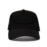 A Von Dutch Triple Black trucker hat shown straight-on against a white background, with a black front panel, curved black brim, black mesh side and back panels, and a tonal black oval Von Dutch logo patch on the front.
